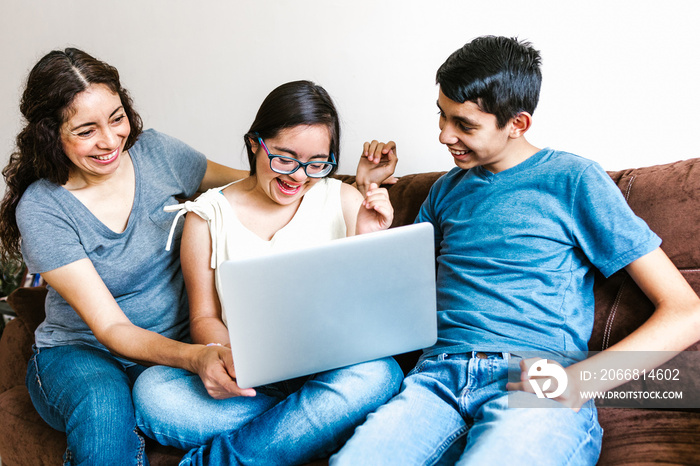 Mexican family and teenage daughter with down syndrome sitting on the sofa with computer at home, in disability concept in Latin America