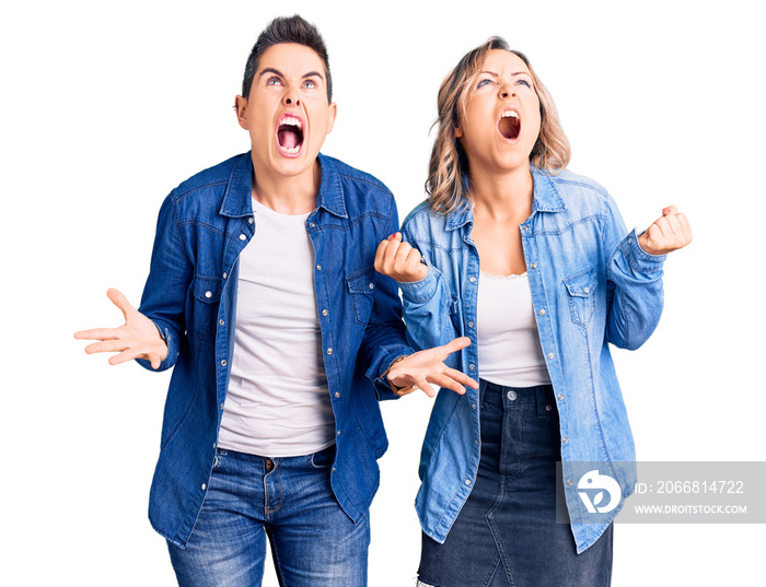 Couple of women wearing casual clothes crazy and mad shouting and yelling with aggressive expression and arms raised. frustration concept.