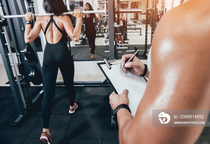 Fitness woman exercising with fitness trainer in gym. Personal fitness instructor.