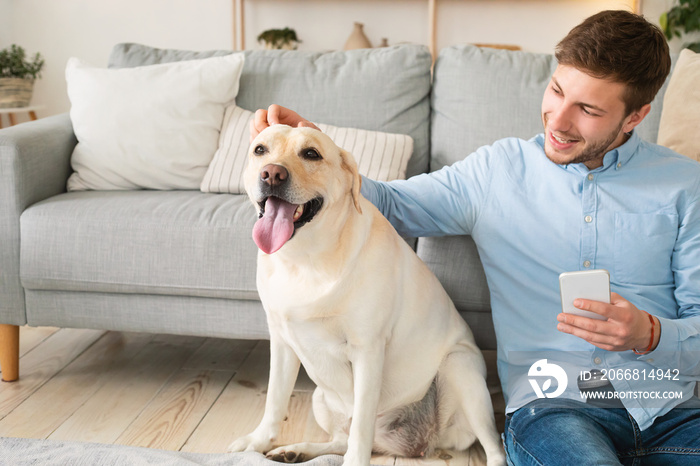 Portrait of guy with his dog using mobile phone