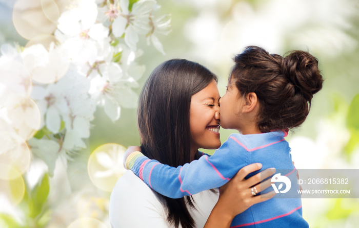 family, motherhood and people concept - happy mother and daughter hugging and kissing over cherry blossom background