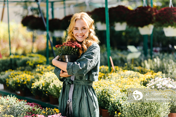 Naughty friendly girl with pretty look loves flora. Portrait in garden of model hugging pot with small pink flowers