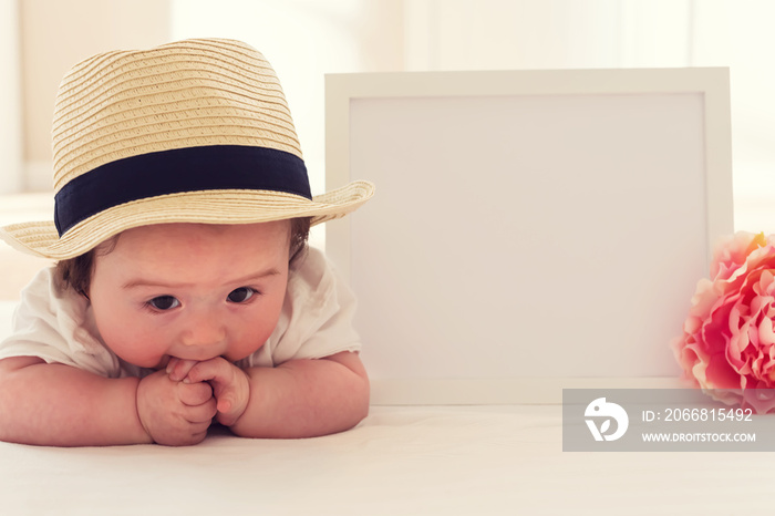 Happy baby boy with photo frame and flower