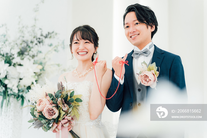 結婚式場で赤い糸で結ばれる新郎新婦（ブライダル・ウェディング）