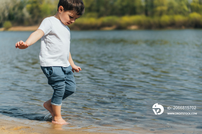 Child walking near lake and looking at water