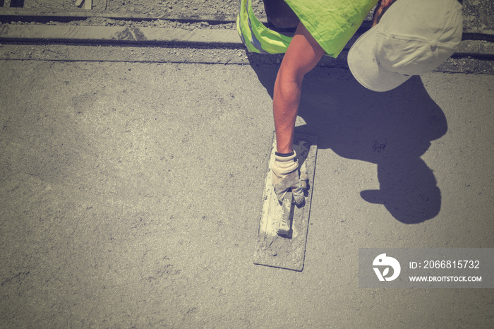 Construction worker leveling concrete pavement.