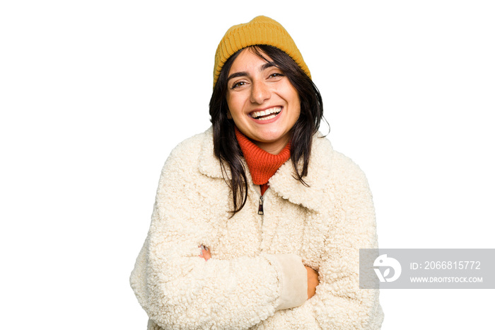 Young Indian woman wearing winter jacket and a wool cap isolated laughing and having fun.