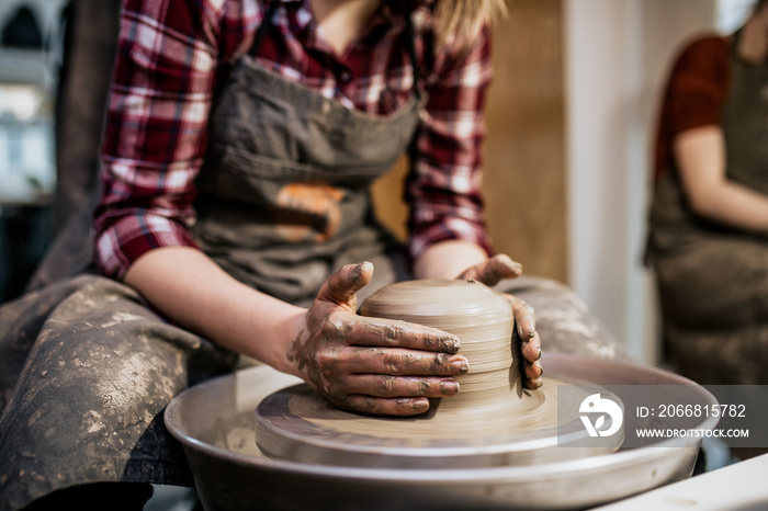 Female potter making clay pottery on a spin wheel.