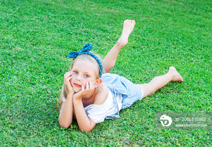 Little girl lying on green grass