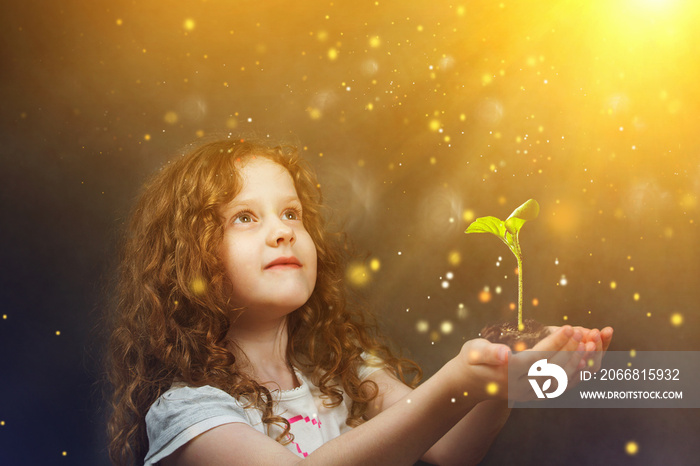 Little girl holding young green plant in sunlight. Ecology conce