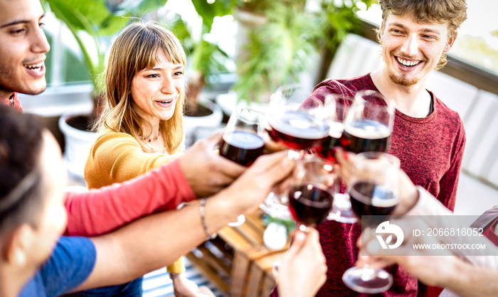 Trendy friends drinking and toasting red wine at rooftop party - Young people having fun together at restaurant winery bar on happy hour - Dining life style concept with bright filter - Focus on woman