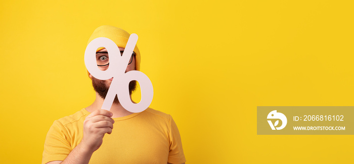 man holding 3D white percentage sign over yellow background, big sales concept, panoramic layout