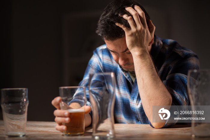 alcoholism, alcohol addiction and people concept - male alcoholic drinking beer from glass at night