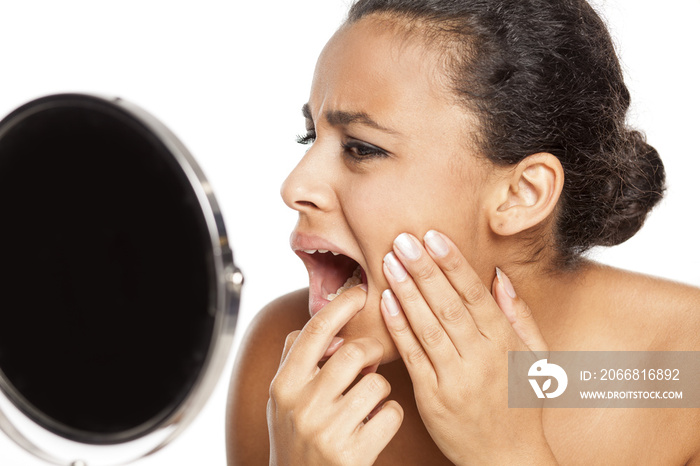 portrait of young dark-skinned woman with tooth ache on white background