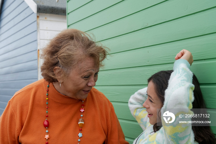 Grandmother standing with granddaughter next to beach hut