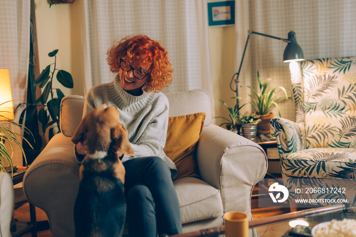 curly red head woman playing with her dog at home