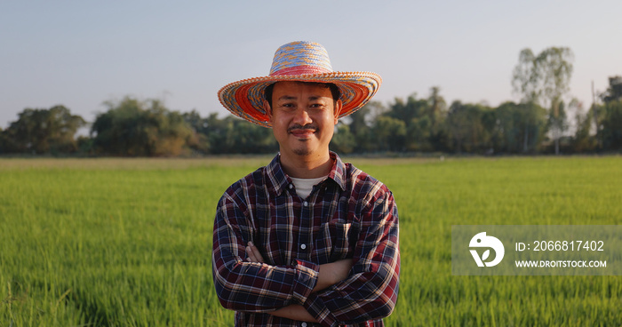 Portrait Happy Asian Farmer arms crossed smiling and looking at camera green paddy field on background.