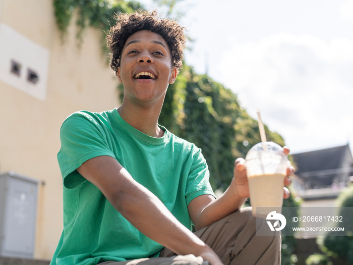 Portrait of young man holding smoothie on sunny day