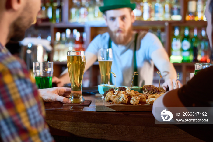 Traditional celebration of Saint Patricks Day: group of friends gathered together in pub, drinking fresh beer and chatting with each other