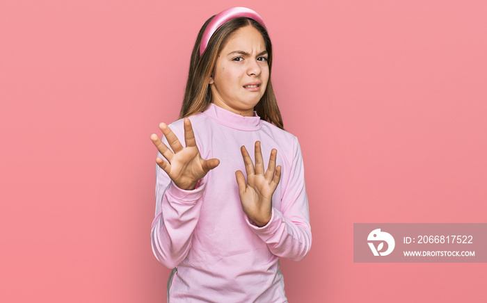 Beautiful brunette little girl wearing casual turtleneck sweater disgusted expression, displeased and fearful doing disgust face because aversion reaction. with hands raised