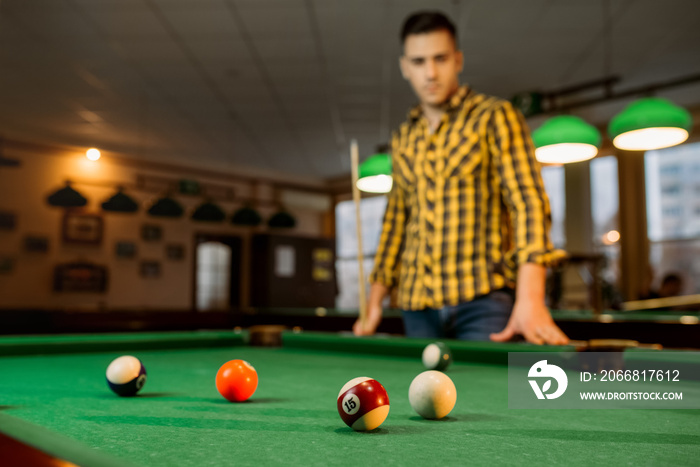 Male billiard player with cue, view from the table