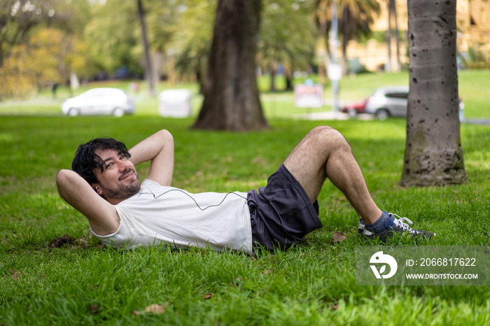 Portrait of handsome attractive mature bearded athletic latin man guy 40s doing sit-ups in the park.