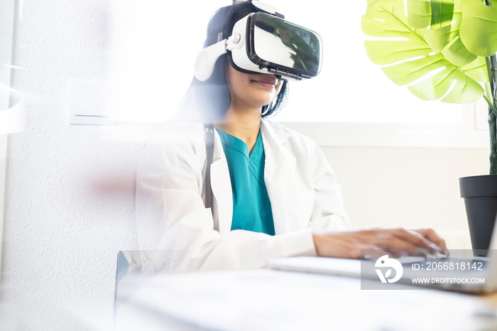 female doctor in office typing on her computer with virtual reality glasses