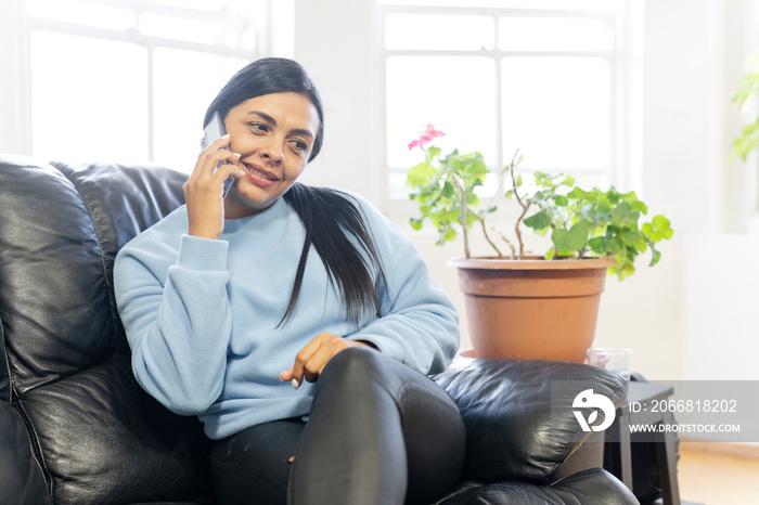 Woman sitting on sofa and talking on phone