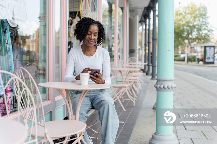 Woman using smart phone during coffee break in sidewalk cafe