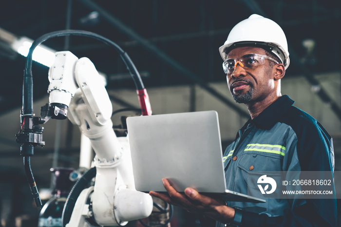 African American factory worker working with adept robotic arm in a workshop . Industry robot programming software for automated manufacturing technology .