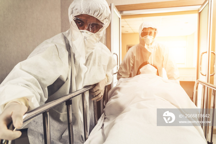 Emergency medic and doctor moving patient to emergency room in hospital . Doctor wears protective suit and face mask in concept of coronavirus and covid 19 protection and quarantine .