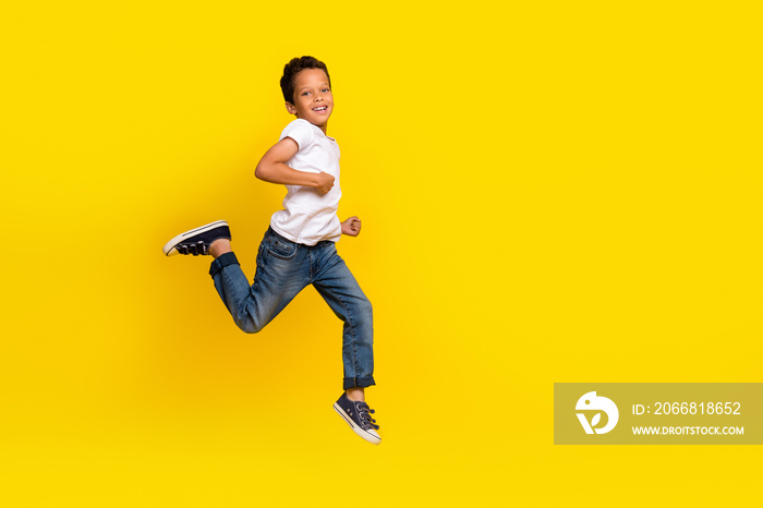 Full body photo of little boy run wear t-shirt jeans sneakers isolated on yellow color background