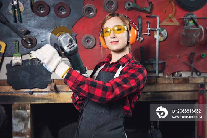 Young female working with grinder machine polishes metal after welding with spark