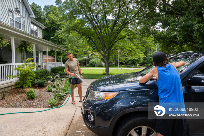 Air Force service member washes his vehicles with his sons in the driveway.