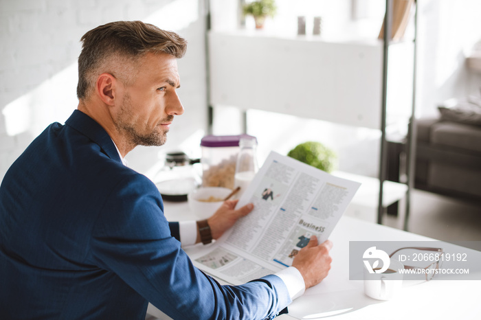 selective focus of confident businessman holding business newspaper