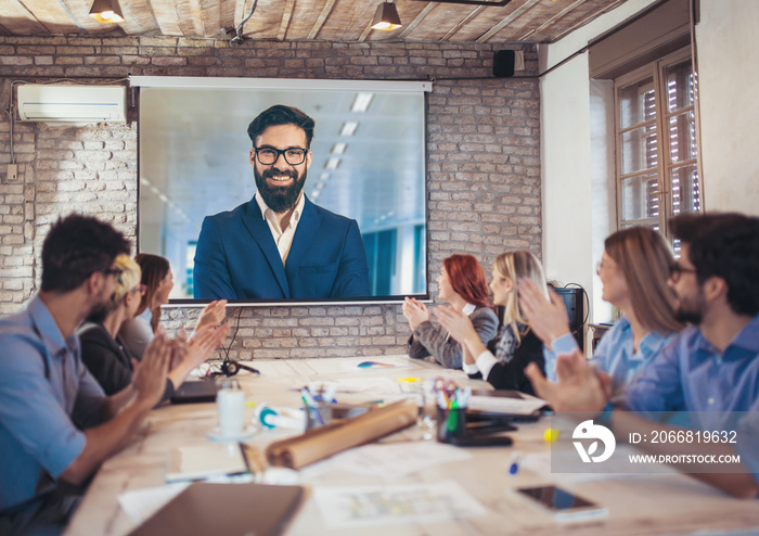 Business people looking at projector during video conference in office