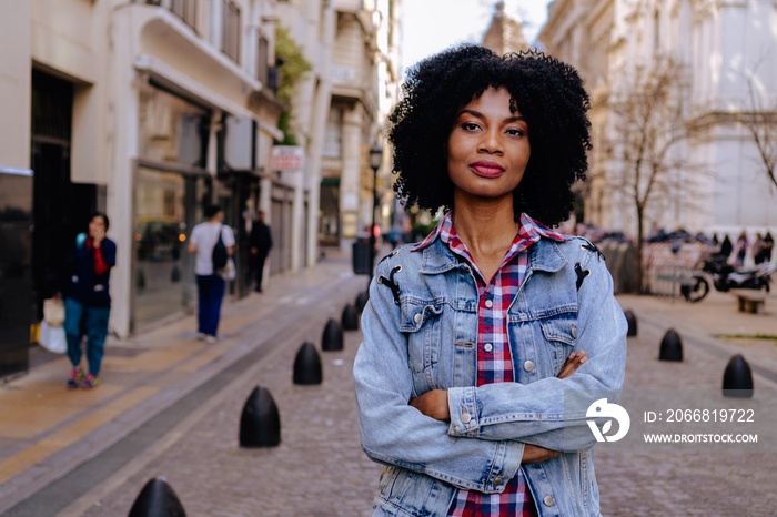 young black haitian woman looks at the camera with crossed arms, urban look and very confident. copy space