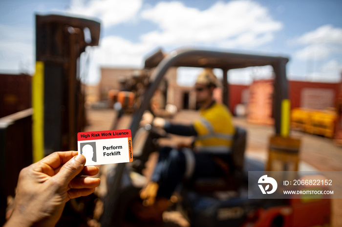 Safe workplace clear image of forklift licence card with defocused forklift driver operator wearing work uniform safety seat belt working mechanical lifting delivery material at the background