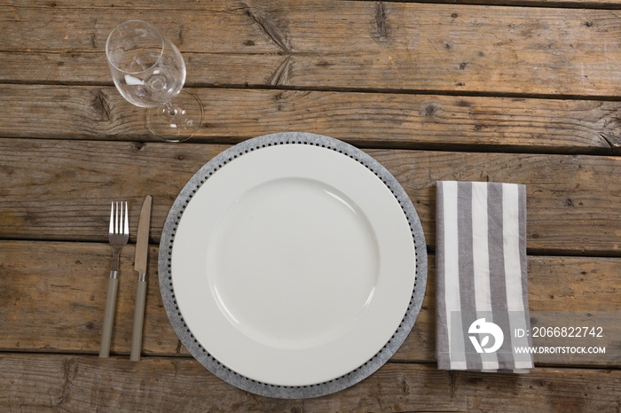 Plate, wine glass, napkin with fork and butter knife on wooden