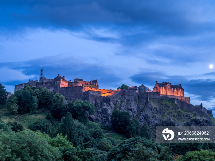 View of Edinburgh Castle looming over the beautiful city of Edinburgh at night.