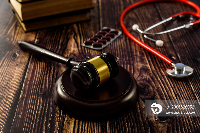 Medical malpractice and errors makes doctors and patients go to court, gavel on legal books.