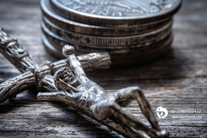 Faith without works is dead (Lat. Fides sine operibus mortua est). Crucifixion of Jesus Christ against money coins background. Concept of charity, resources and opportunities for material assistance.