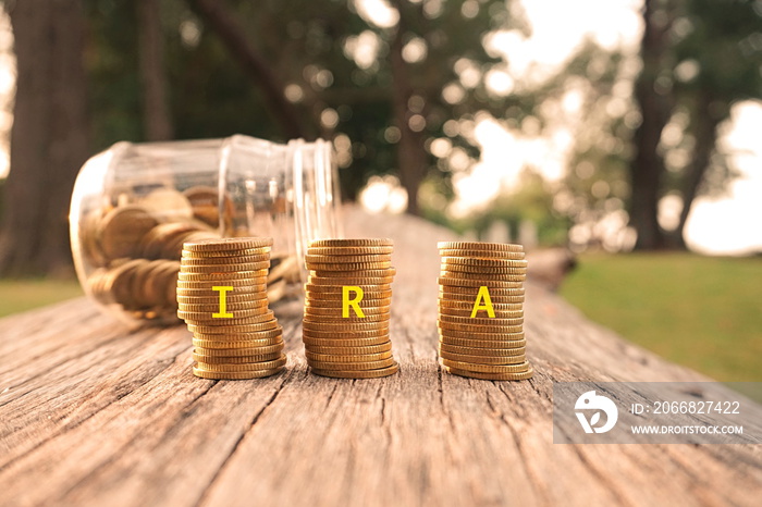 Close up of stacking gold coins written IRA on nature background and natural lighting. Individual Retirement Account concept