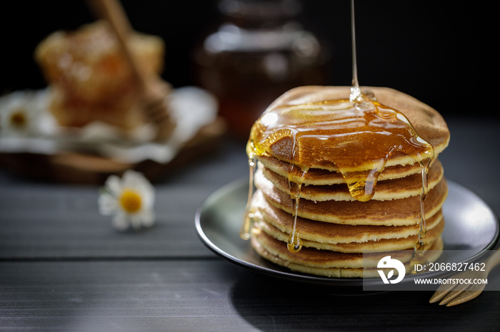 Honey dripping on the stack of pancakes for breakfast on the wooden table, healthy products by organic natural ingredients concept