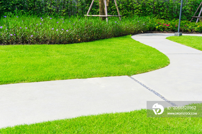 Gray walkway on green grass lawn in garden, sand washed finishing pavement