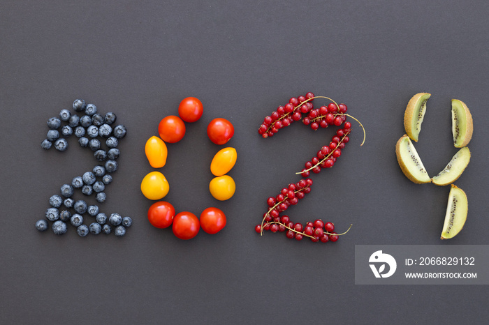 Happy New Year 2024 number made of fruits and berries on black