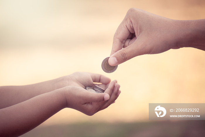 Mother giving coin to child as saving money concept in vintage color tone