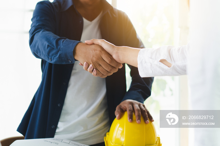 Successful deal, male architect shaking hands with client in construction site after confirm blueprint for renovate building.