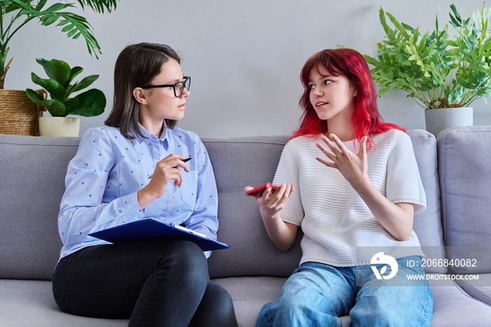 Psychologist counseling teenage female, individual therapy in doctors office.