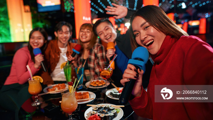 Singing into microphone and making selfie at karaoke party in club